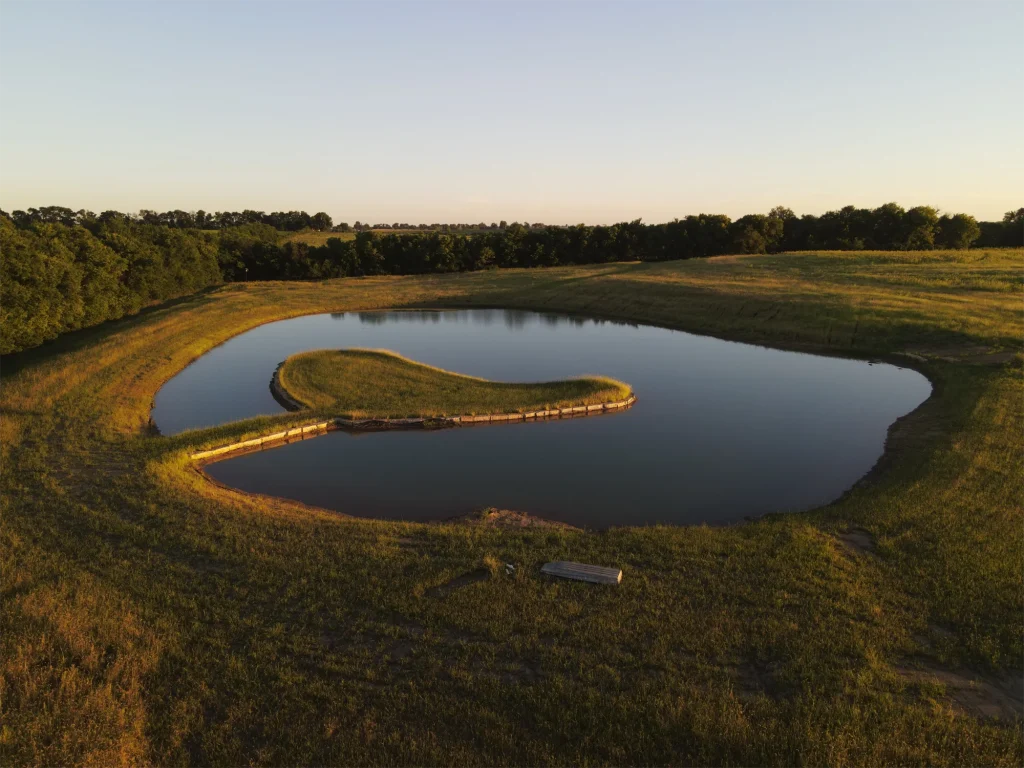 Gorgeous Acreage Pond Installation Project with limestone rock visible around the perimeter of the island