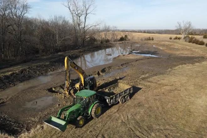 A pond being mucked out using heavy equipment