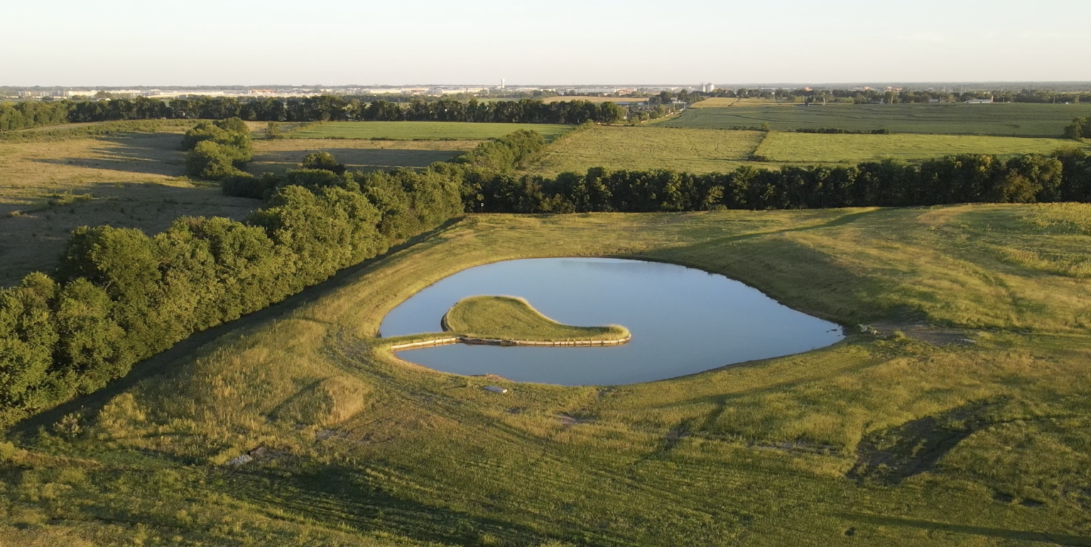Aerial view of a 3-acre upscale pond with a limestone-lined peninsula in Gardner, Kansas, designed and built by Bulletproof