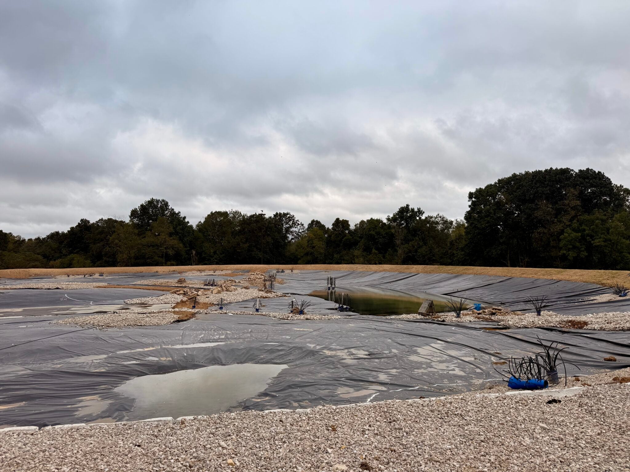 Fish structure, rock habitat and gravel shelves being installed across a geosynthetic lined pond during construction by Bulletproof