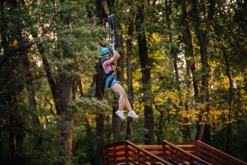 Rider on a private backyard zipline through the trees, a creative addition for pond and lake properties